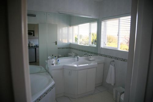 a white bathroom with a tub and a sink and a bath tub at Majorca House in Somerset West