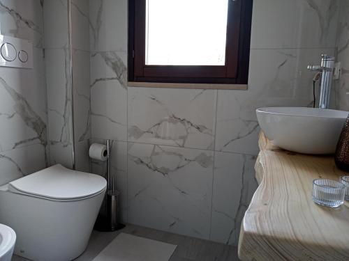 a bathroom with a toilet and a sink and a window at B&B Tra mare e montagna - sauna e piscina in San Giorgio di Pesaro
