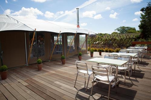 una terrazza con tavoli, sedie e tenda bianca. di Durrell Wildlife Camp a Trinity