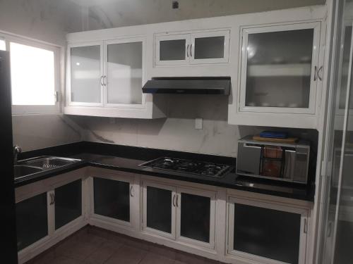 a kitchen with white cabinets and a stove top oven at Casa Horizonte Azul Acapulco in Acapulco