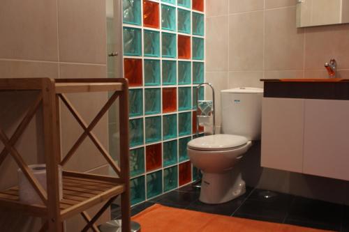 a bathroom with a toilet and a colorful tile wall at Casa Da Baía in Lagos
