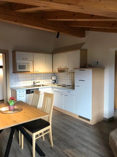 a kitchen with white cabinets and a wooden table and chairs at Ritterhof in Fiss