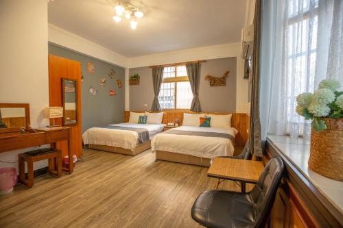 Una habitación de hotel con dos camas y un escritorio. en 阿鑫民宿, en Jinning