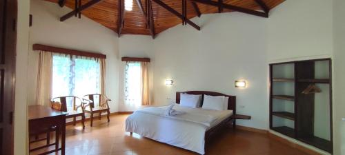 a bedroom with a bed and a desk and windows at Bara Beach Bungalows in Bira