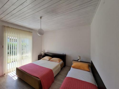 a bedroom with two beds and a large window at Guest House Barba in Bibinje