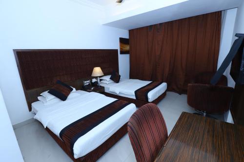 ein Hotelzimmer mit 2 Betten, einem Tisch und Stühlen in der Unterkunft Hotel Kohinoor in Bharūch
