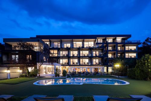 a large building with a pool in front of it at Hotel Finkenhof - Feel at home in Schenna