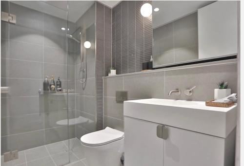 a bathroom with a toilet and a sink and a shower at Box Hill Central Sky One Apartment in Box Hill