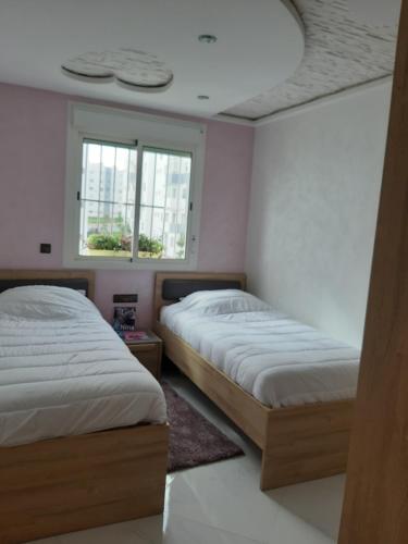 a bedroom with two beds and a window at perle rare plage des Nations in Sidi Bouqnadel