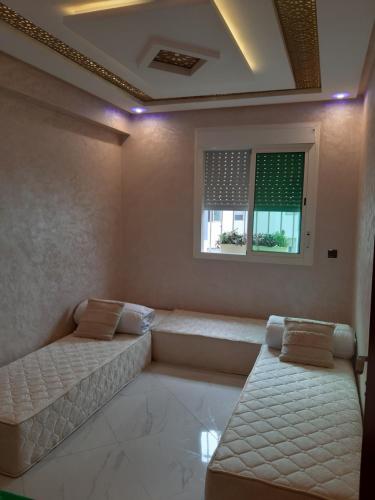 a room with two beds and a window at perle rare plage des Nations in Sidi Bouqnadel