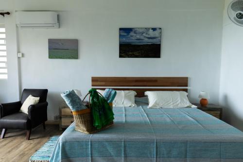 a bedroom with a bed with a blue blanket and a chair at Villa Mon Refuge in Tambe