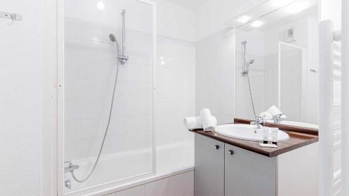 a white bathroom with a shower and a sink at Madame Vacances Les Rives Marines in Le Teich