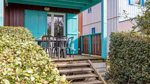 a blue house with a table and chairs on a porch at Madame Vacances Les Rives Marines in Le Teich