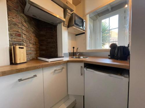 a kitchen with white cabinets and a brick wall at Coconut Beach apartments in Zandvoort