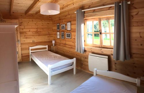 Cabaña de madera con cama y ventana en Le Chalet Caux-Marin, en Tourville-la-Chapelle