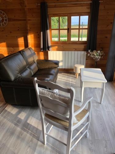 a living room with a leather couch and a table at Le Chalet Caux-Marin in Tourville-la-Chapelle