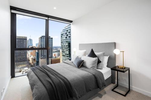 a bedroom with a large bed and a large window at Luxuria Apartments - Collins House in Melbourne