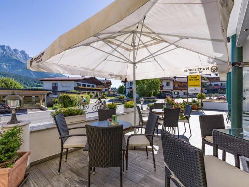 a patio with tables and chairs and an umbrella at Apparthotel Tom Sojer in Ellmau