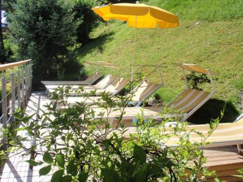 a group of lounge chairs and an umbrella at Hotel Metzgerwirt in Fieberbrunn
