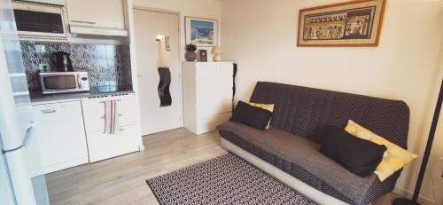 un petit salon avec un canapé et une cuisine dans l'établissement Les Marines d'Agay Studio climatisé, à Saint-Raphaël
