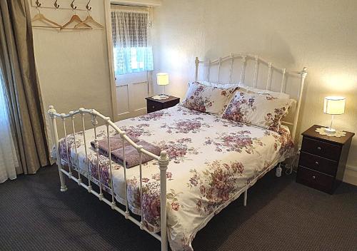 a bedroom with a bed and two night stands with lamps at Miss Mabel Cottage in Burra