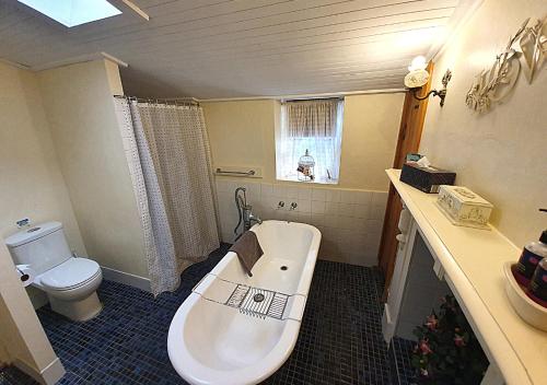 a bathroom with a bath tub and a toilet at Miss Mabel Cottage in Burra