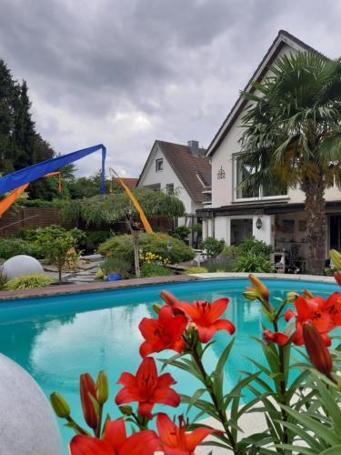 a swimming pool with red flowers next to a house at Haus Steffi in Müllheim