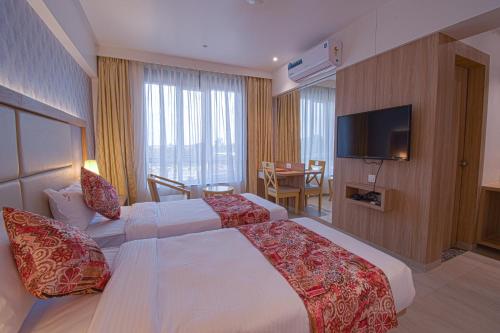 a hotel room with two beds and a television at Hotel Park Tree, NEAR 5 STAR MIDC, KANERIWADI, NH4 GOA HIGHWAY KOLHAPUR in Kolhapur