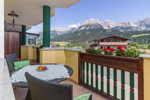 a balcony with a table and chairs and mountains at Apparthotel Tom Sojer in Ellmau