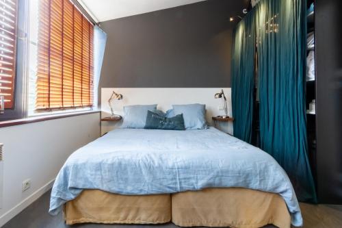 - une chambre dotée d'un grand lit avec des draps bleus et des fenêtres dans l'établissement Portus, à Pornichet