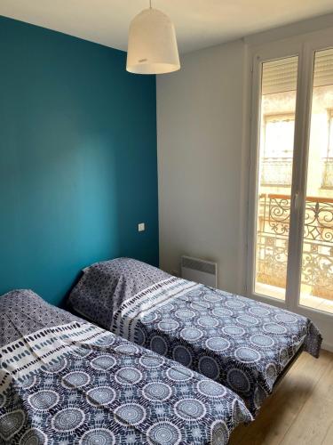 Ce lit se trouve dans une chambre dotée d'un mur bleu. dans l'établissement Appartement climatisé SETE - Rue MONTMORENCY, à Sète