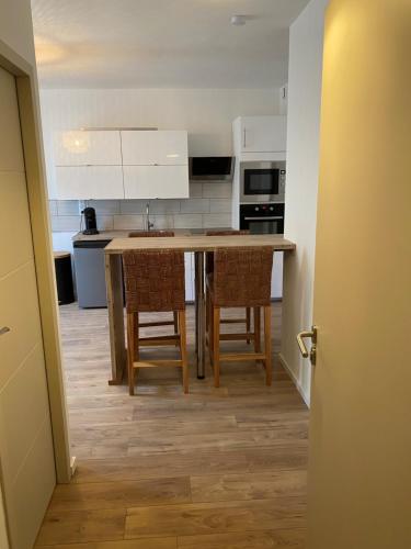 une cuisine avec une table, des chaises et des armoires blanches dans l'établissement Appartement climatisé SETE - Rue MONTMORENCY, à Sète