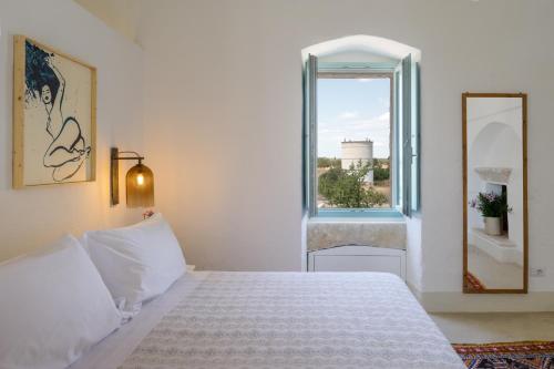 a white bedroom with a bed and a window at Masseria Palombara Relais & SPA - Adults only in Manduria