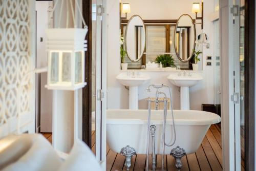 a bathroom with two sinks and a tub and mirrors at The Shore At Katathani - Adult Only - SHA Extra Plus in Kata Beach