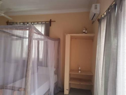 een slaapkamer met witte gordijnen en een raam bij Heart of Zanzibar Bungalows in Paje