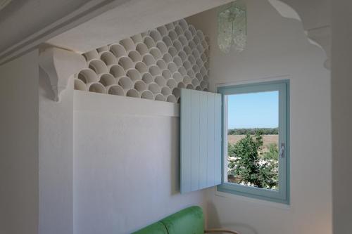 a living room with a window and a green couch at Masseria Palombara Relais & SPA - Adults only in Manduria