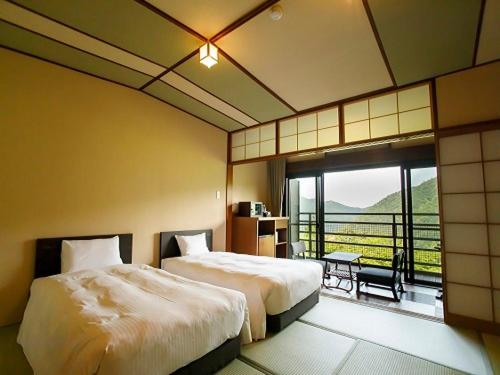 a hotel room with two beds and a balcony at Hakone Kowakien Mikawaya Ryokan in Hakone