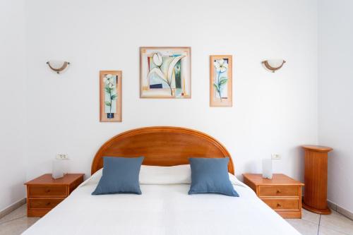 una camera da letto con un letto con due comodini e tre immagini sul muro di Casa Naranja - Heated Pool - BBQ - Terrace - Free Wifi - Child & Pet-Friendly - 3 bedrooms - 6 people a Poris de Abona