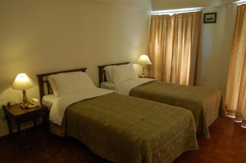 two beds in a hotel room with two lamps at The Meadows Resort and Spa in Aurangabad