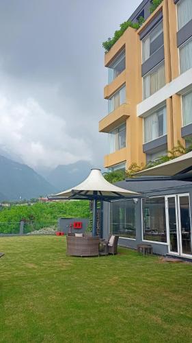a building with an umbrella and chairs in a yard at Welcomhotel By ITC Hotels, Katra in Katra
