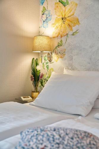 a bedroom with a bed with a lamp and flowers on the wall at Hotel Monopol - Central Station in Frankfurt/Main
