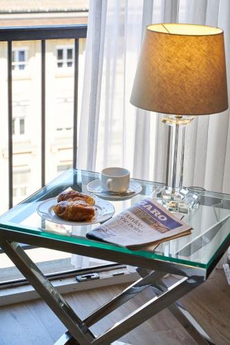 a glass table with a plate of food and a lamp at Hotel Monopol - Central Station in Frankfurt/Main