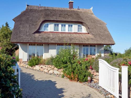 uma casa com telhado de palha e uma cerca branca em Reethus Reddevitz F 402 mit Kamin, Sauna, Terrasse, Boddenblick em Alt Reddevitz