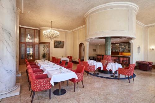 a dining room with white tables and red chairs at Hotel Monopol - Central Station in Frankfurt/Main