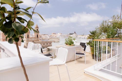 a balcony with white chairs and tables and a view of the city at Plaza Mina Suites - Adults Recommended by Luxury Suites Cadiz in Cádiz