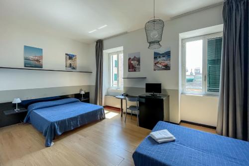 a bedroom with two beds and a desk with a computer at Hotel Britannia in Genova