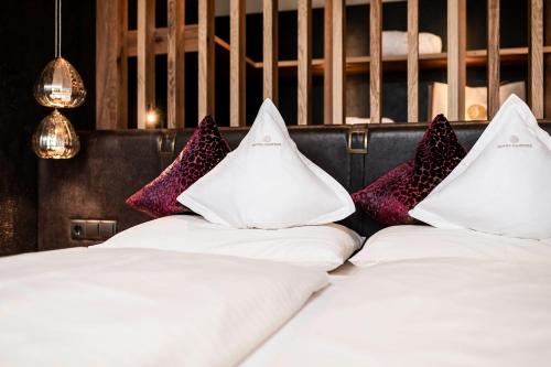 a row of white beds with colorful pillows at Hotel Santner Alpine Sport & Relax in Alpe di Siusi
