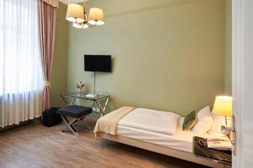 a bedroom with a bed and a desk and a television at Hotel Monopol - Central Station in Frankfurt/Main