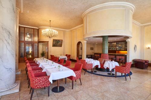 a dining room with white tables and red chairs at Hotel Monopol - Central Station in Frankfurt/Main