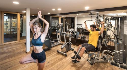 a man and a woman exercising in a gym at Hotel Santner Alpine Sport & Relax in Alpe di Siusi